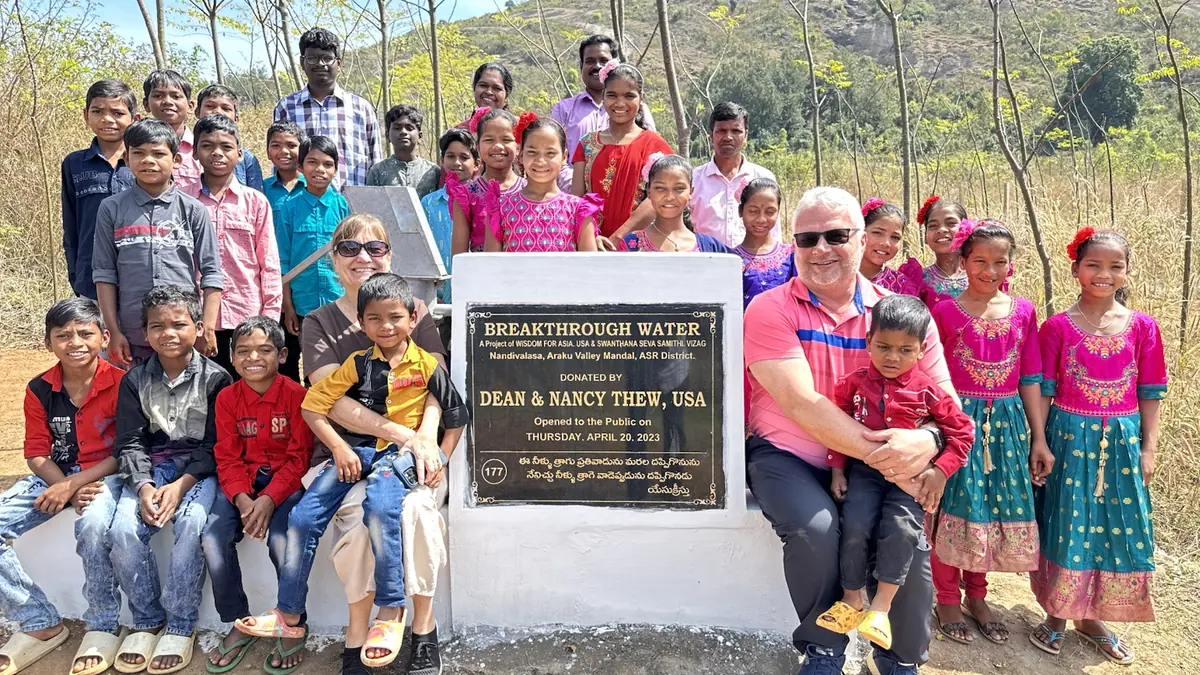 Children and project partners stand behind a completed Breakthrough Water hand pump.