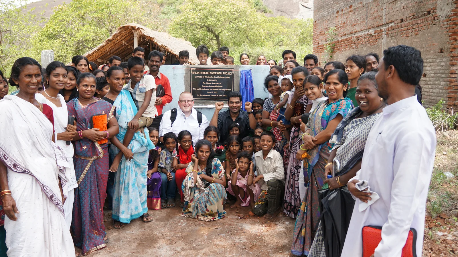 Women, men, and children gather around the plaque of the first Breakthrough Water well in Makkuva.